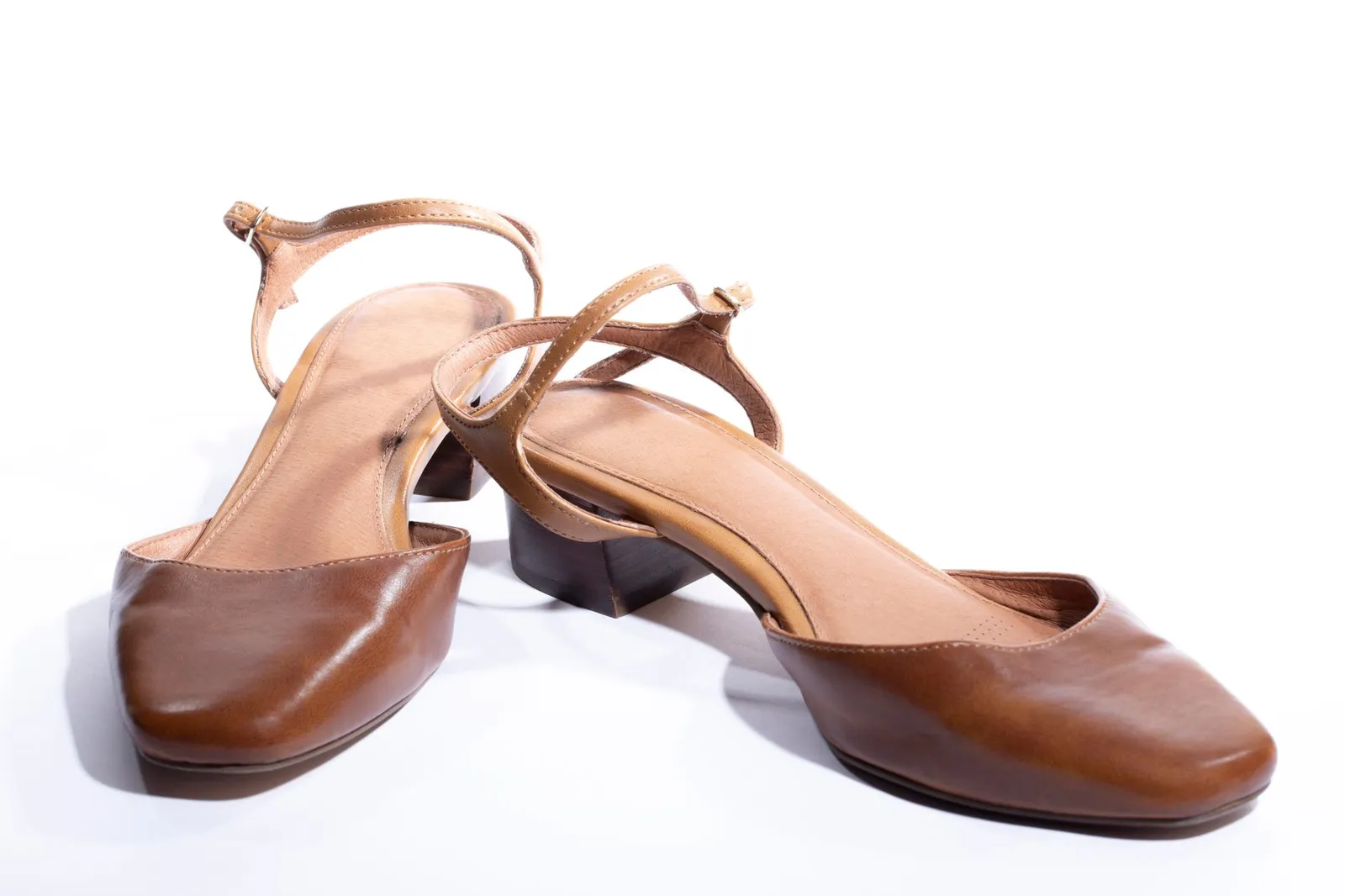 Pair of brown leather strappy heeled sandals on a white background