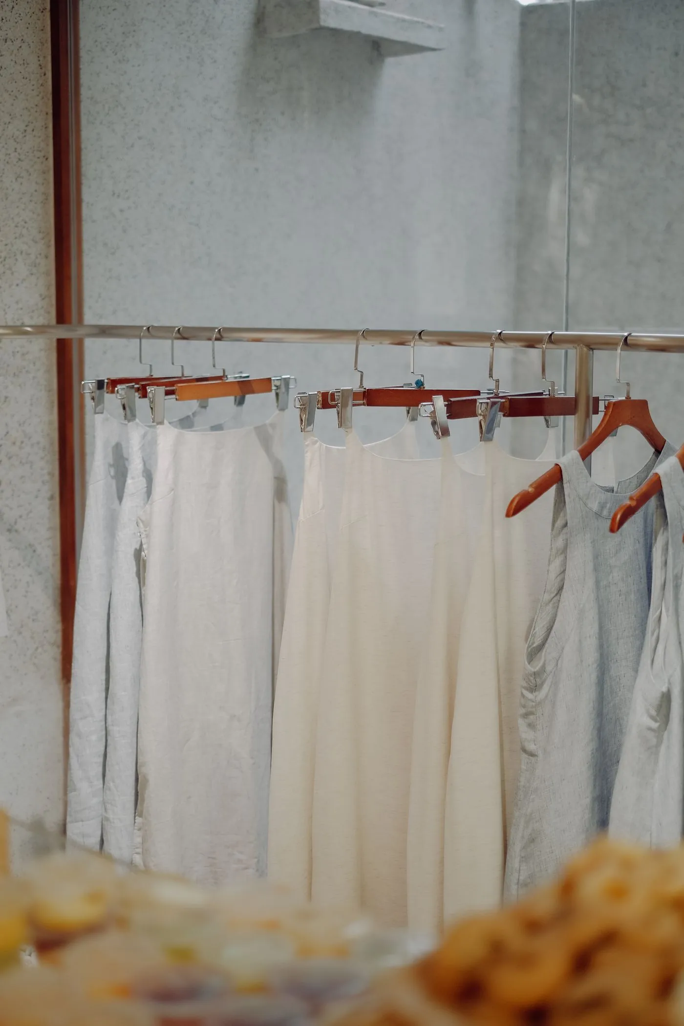 Robes blanches et écrues sur un portant dans une boutique aux tons neutres