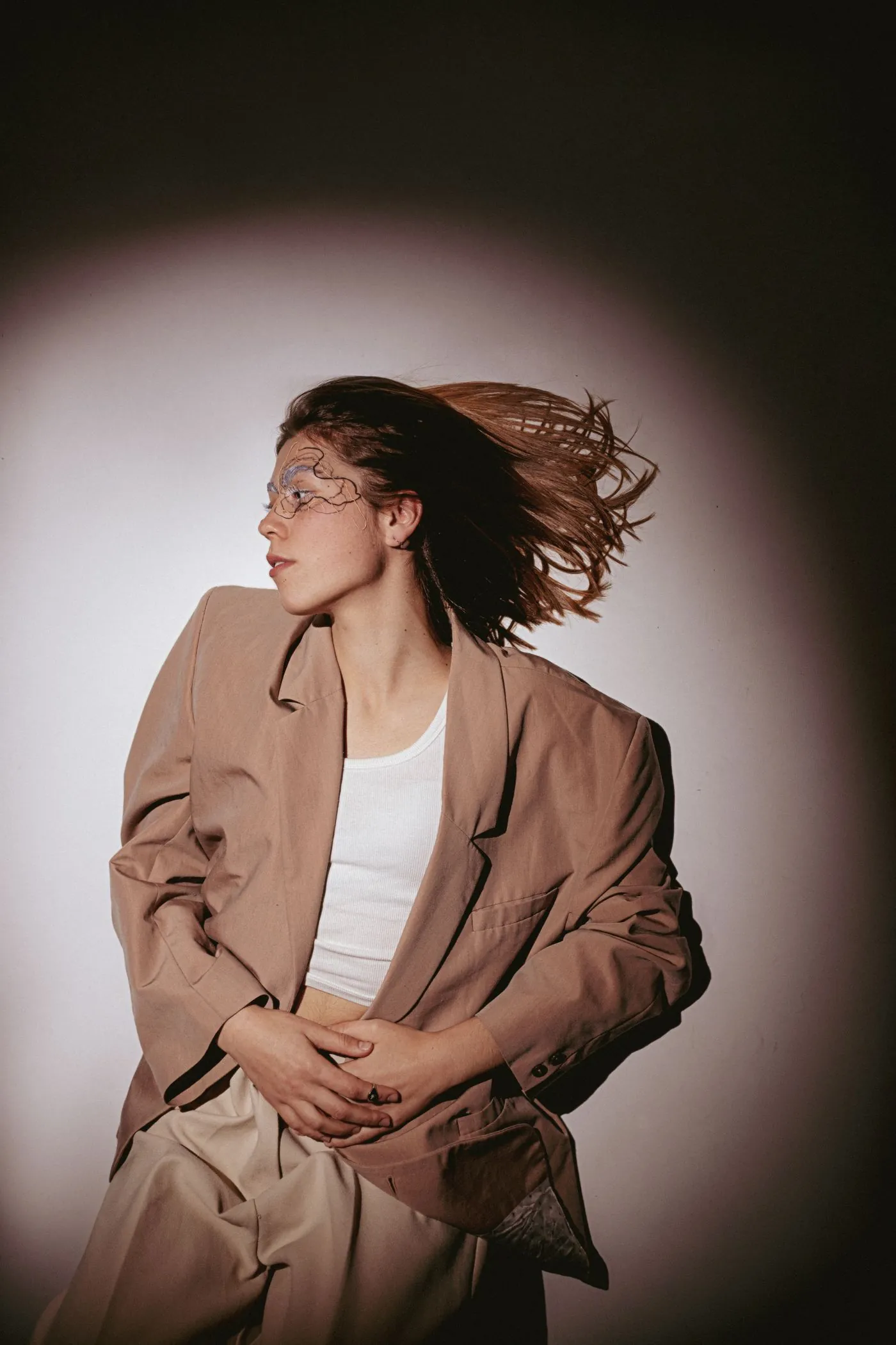Femme en tailleur beige et lunettes, portrait en lumière contrastée