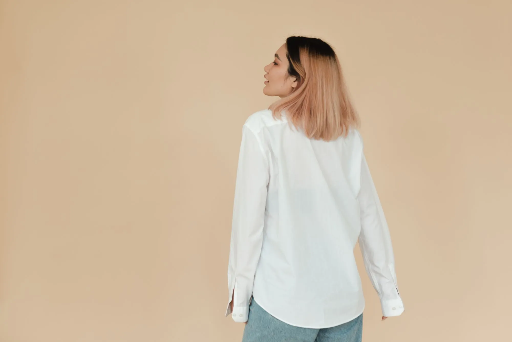 Femme en chemise blanche sur fond beige